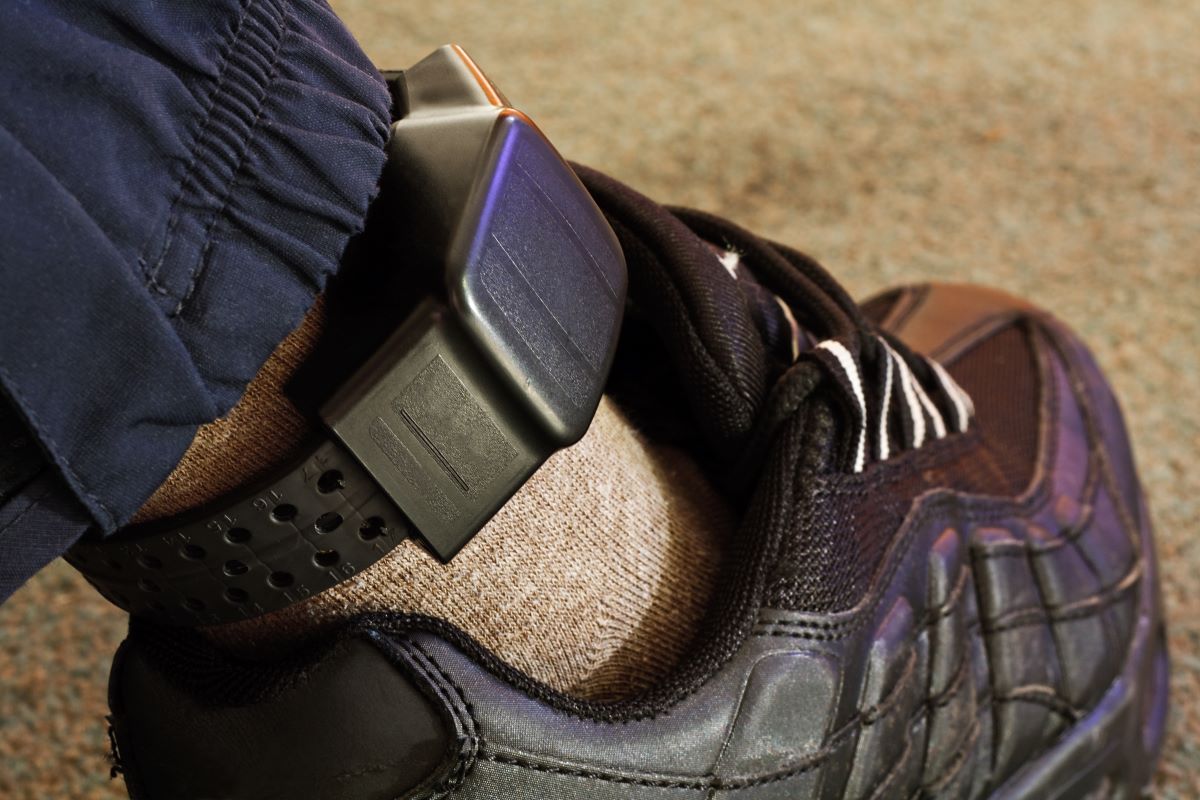 Man on house arrest wearing ankle monitoring device